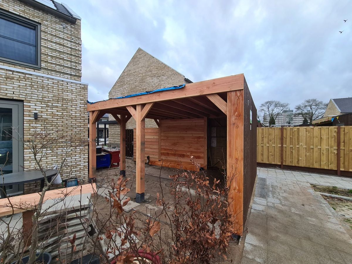 Overkapping met houten gevelbekleding tegen een hoekwoning